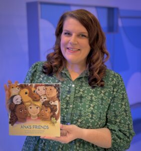 article image - (1) A.N.A.’s Friends CEO Jessica Kaestner holding Ana’s Friends book